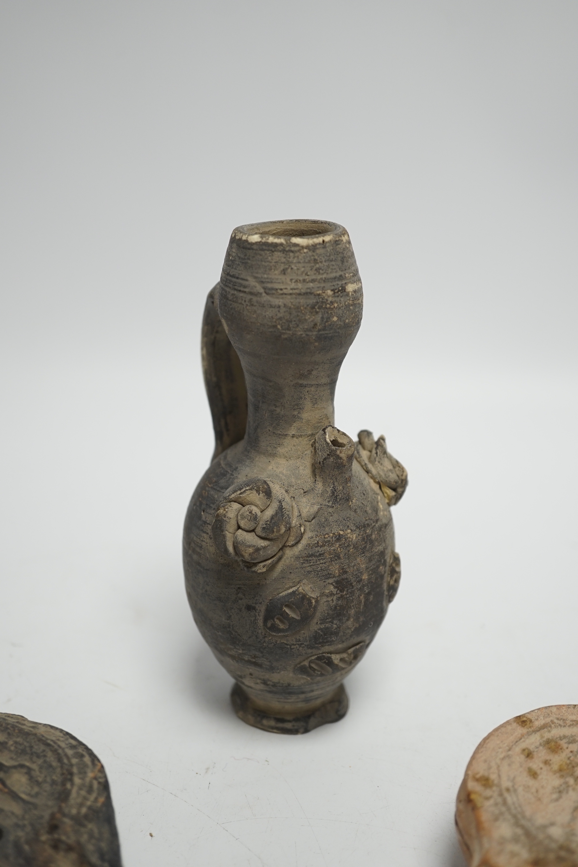 Two Roman oil lamps and an early ewer, tallest 14.5cm